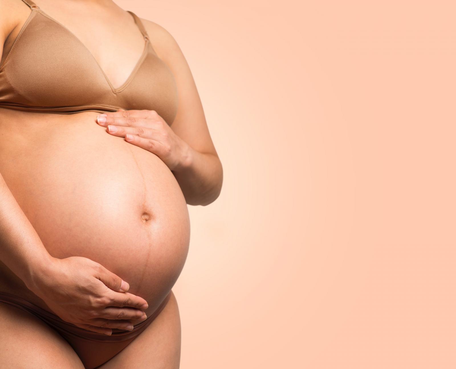 Une femme enceinte en sous-vêtements qui touche à son ventre