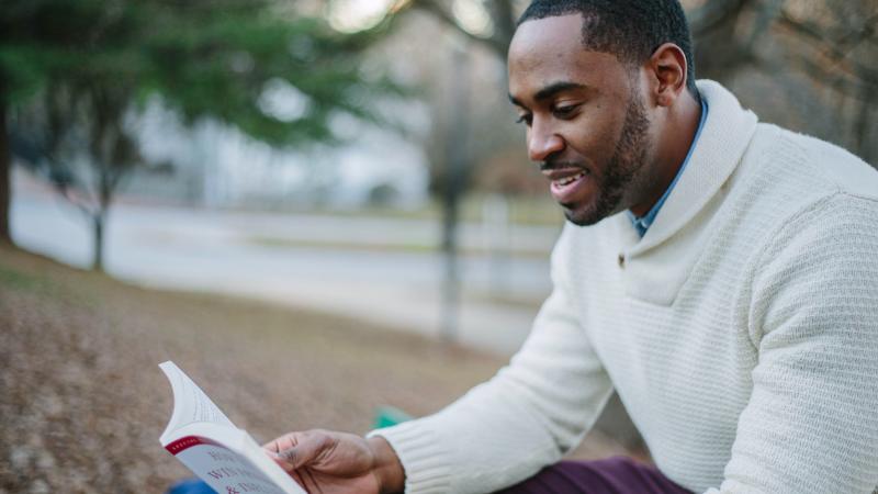 Un homme qui lit un livre dans un parc