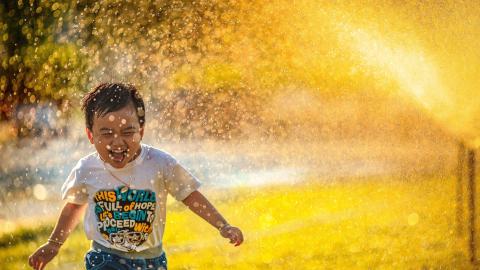 Un enfant qui court sous un jet d'eau